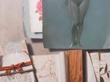 a painting of a naked woman hanging on a wall next to a pile of books