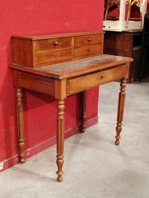 a small desk with a drawer on it in front of a red wall