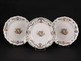 three plates with floral designs on them sitting on a black surface