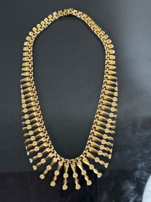 a gold necklace on display in a glass case