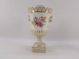 a white vase with flowers on it sitting on a table