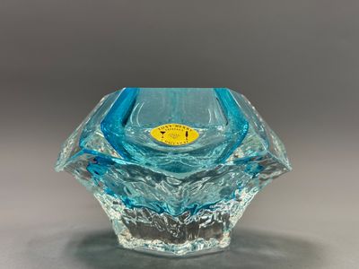 un vase en verre bleu sur lequel est collé un autocollant jaune