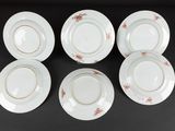 six white plates with gold rims on a black surface