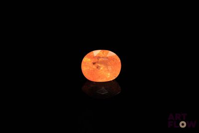 an orange stone on a black surface in the dark