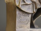 a bronze statue of a woman with a hat on her head