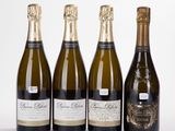 four bottles of champagne are lined up on a white surface