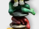 a statue of a man sitting on top of a stack of plates