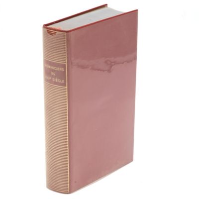 a pink book sitting on top of a white table next to a white wall