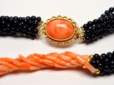 two black and orange beaded necklaces with a gold clasp