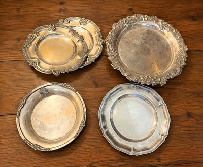 quatre assiettes en argent posées sur une table en bois, dont une est vide et une autre est vide