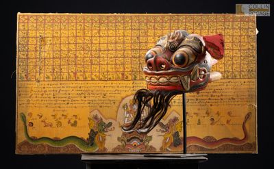 un masque en bois posé sur un socle, avec une carte en arrière-plan