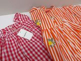 two red and white gingham dresses on display in a box