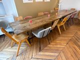 une longue table avec des chaises et un vase posé dessus, dans une pièce