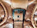 a close up of a brown leather bag with a metal buckle