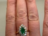 an image of a woman ' s hand holding a green and white diamond ring