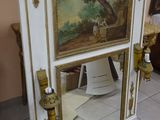 a mirror with a painting on it in the corner of a room