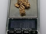 a gold cross on a scale with a chain on it