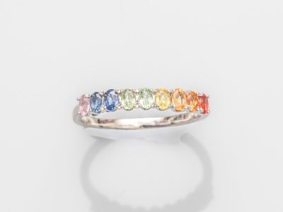 un gros plan d'une bague aux couleurs de l'arc-en-ciel posée sur une surface blanche