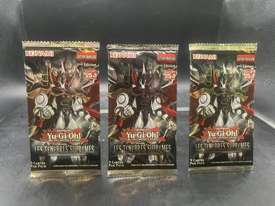 Trois paquets de boosters Yu-Gi-Hah sont posés sur une table