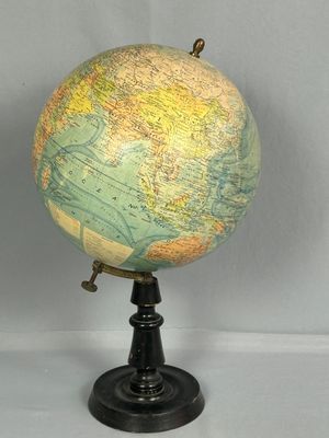 un petit globe terrestre posé sur un socle, sur une table