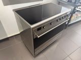 stainless steel stove with glass top in a kitchen with a refrigerator in the background