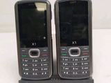 two cell phones sitting on a stand on a table