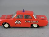 a red toy car with a fire chief on the side of it
