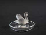 a glass swan sitting on top of a glass plate