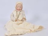 a small doll sitting on a blanket on a white surface