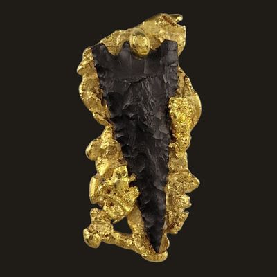 a close up of a piece of gold on a black background