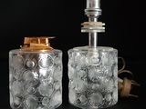 Deux bouteilles en verre transparent munies de bouchons dorés sont posées l'une à côté de l'autre