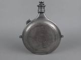 an antique silver flaskt with a handle on a gray background