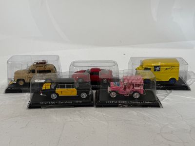 four toy cars in a display case on a white surface