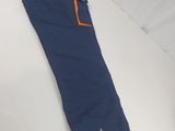 Le pantalon est bleu et orange, avec une fermeture éclair au bas.