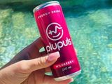 une personne tenant une canette de Red Bull près d'une piscine