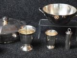 une assiette en argent et des tasses en argent posées sur un fond noir