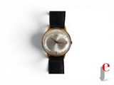 une photo d'une montre posée sur une surface blanche, avec un bracelet noir