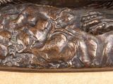 a bronze statue of a dog laying down on the ground
