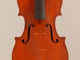 an old violin hanging from a string on a white wall