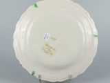 underside view of a white plate with green trim on a metal stand