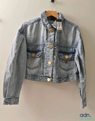 une veste en jean suspendue à un cintre accroché au mur