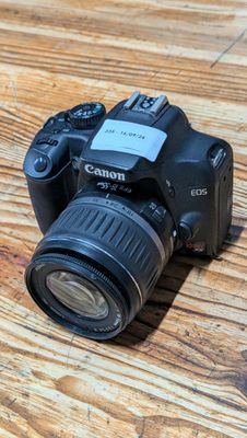 a camera sitting on a wooden table with a lens attached to it