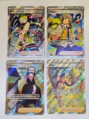 quatre cartes Pokémon différentes posées sur une table avec un fond blanc