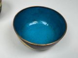 a blue bowl sitting next to a brown bowl on a table