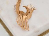 broche en forme de paon plaquée or posée sur un socle en marbre blanc