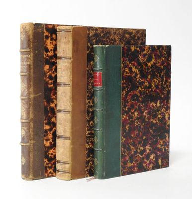 three old books are stacked on top of each other on a white surface