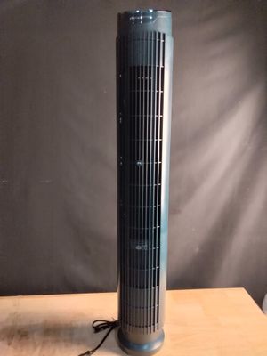 un ventilateur électrique posé sur une table en bois, à côté d'une lampe
