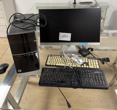 un ordinateur de bureau et un clavier posés sur une table en verre