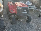 a lawn mower that is parked next to a tractor