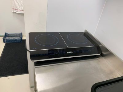 une plaque de cuisson noire posée sur un plan de travail en acier inoxydable